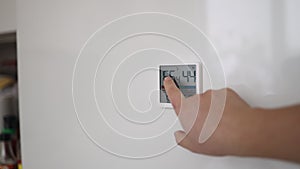 Woman hand press button activate smart home system at home. Female use modern security equipment or alarm control panel