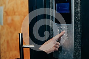 Woman hand press buttons on video intercom at entrance of apartment building in the night