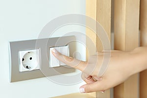 Woman hand pressing light switch