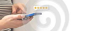 Woman hand pressing on smartphone screen with gold five star rating feedback icon, review the service business concept