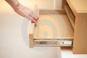 Woman hand pull open drawer wooden cabinet