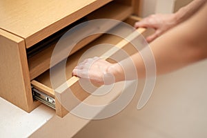 Woman hand pull open drawer wooden cabinet