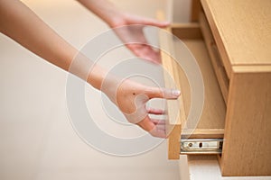 Woman hand pull open drawer wooden cabinet