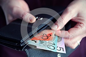 Woman hand pulling out Australian money from a wallet