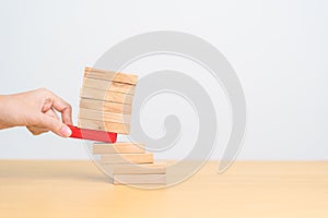 woman hand pulling wood domino blocks on table. Crisis, fall Business, Risk management, Economic recession, Strategy and solutions