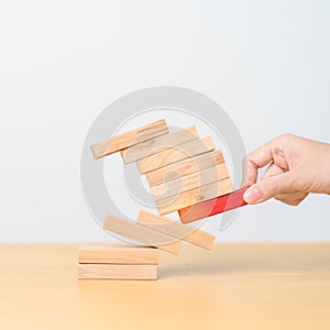 woman hand pulling wood domino blocks on table. Crisis, fall Business, Risk management, Economic recession, Strategy and solutions