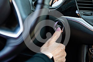 Woman hand pushing on car engine start-stop button. Modern car interior, closeup