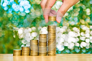 Woman hand put coin on step of coins stacks and gold coin money