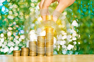 Woman hand put coin on step of coins stacks and gold coin money