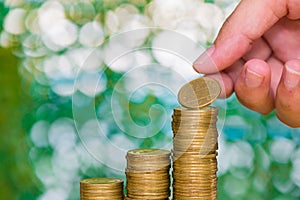 Woman hand put coin on step of coins stacks and gold coin money