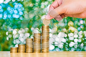 Woman hand put coin on step of coins stacks and gold coin money