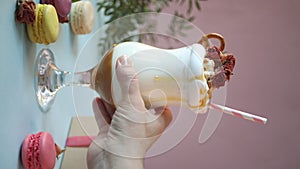 Woman hand put on table milkshake with caramel syrup, popcorn and brezel waffles decorating dry rose