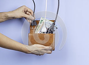 Woman hand puts electric power plugs in open wallet with Euro banknotes. Energy efficiency, power consumption, rising