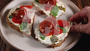 Woman hand puts ham cheese sandwich on plate, ready to eat bruschetta, close up