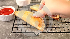 Woman hand puts Mexican fried meat pies empanadas cheburek on the baking rack