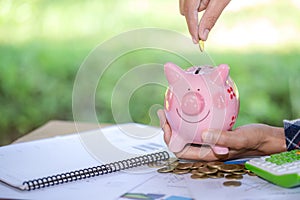 Woman hand putting coin into piggy bank. Saving money wealth and