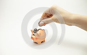 Woman hand putting coin into piggy bank. Saving money wealth and financial concept