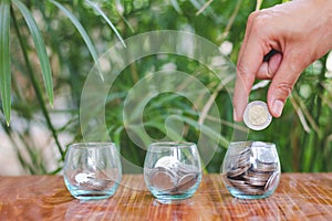 Woman hand putting coinIn the glass jar. Saving money wealth and financial concept