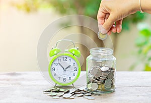 Woman hand putting Coins in glass jar for money saving for retirement concept