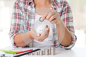 Woman hand putting money coin into piggy bank.