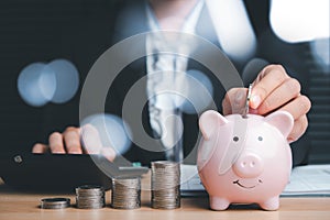 Woman hand putting money coin into piggy bank for saving money