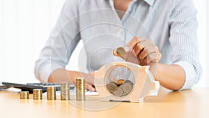 Woman hand putting money coin into piggy bank with step of growing stack coins for saving money for future investment concept