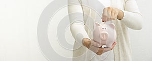 Woman hand putting money coin into piggy for saving money wealth and financial concept