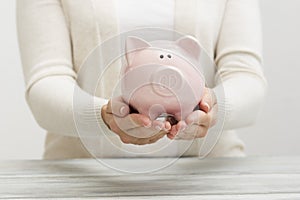 Woman hand putting money coin into piggy for saving money wealth and financial concept.