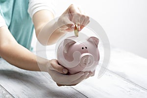 Woman hand putting money coin into piggy for saving money wealth and financial concept.