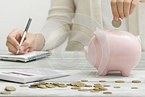 Woman hand putting money coin into piggy for saving money wealth and financial concept.