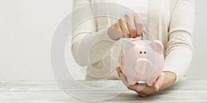 Woman hand putting money coin into piggy for saving money wealth and financial concept