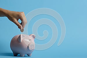 Woman hand putting money coin into piggy for saving money wealth and financial concept