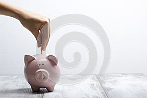 woman hand putting money coin into piggy for saving money wealth and financial concept