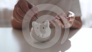 woman hand putting money coin into piggy for saving money wealth and financial concept.