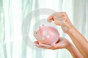 Woman hand putting money coin in to piggy for saving money wealth and financial concept