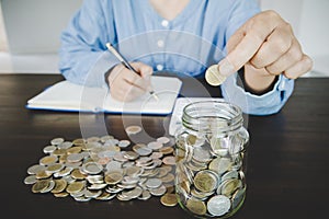 woman hand putting money into jar