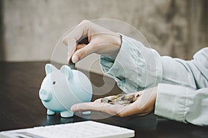 woman hand putting money into piggy