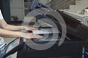 Woman hand putting a sheet of paper into a copying device