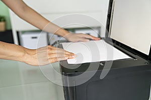 Woman hand putting a sheet of paper into a copying device, photocopy or xerox photo