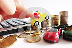 Woman hand putting toy car on money coins stack growing, suggesting increase cost for car