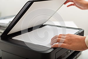 Woman hand putting white paper in printer, scanner,  copy machine, office document, photocopier