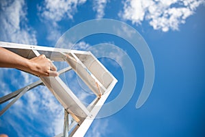 Woman Hand Reaching For Red Ladder Leading To A Blue Sky