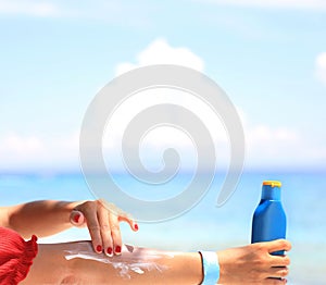Woman hand with red cloth and healthy skin applying sunscreen to shoulder which she is  protection of sunburn and cancer