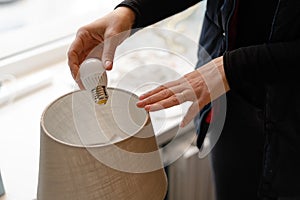 Woman hand replacing light bulb for energy saving one. Energy efficiency at home