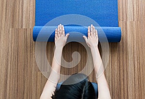 Woman hand rolling or folding blue yoga mat after a workout,Exercise equipment,Top view Healthy fitness and sport concept