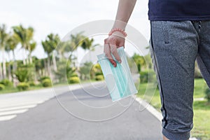 Woman hand`s hold medical protective mask in the garden park. Prepare for protect virus or COVID19