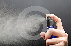 Woman hand's holding bottle spray against gray background photo