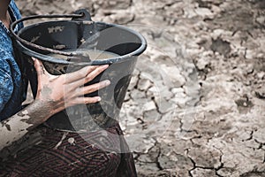 Woman hand are scooping water on cracked ground.