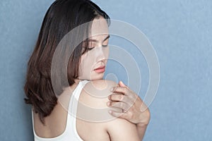 Woman hand scratching her shoulder with grey background, health care and medical concept