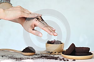 Woman hand with scrub coffee grounds on wooden background, Beauty and healthy care concept